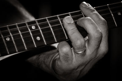 Close-up of man playing guitar against black background