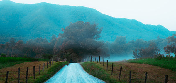 Road amidst field against sky