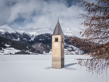 Built structure on snowcapped mountain against sky