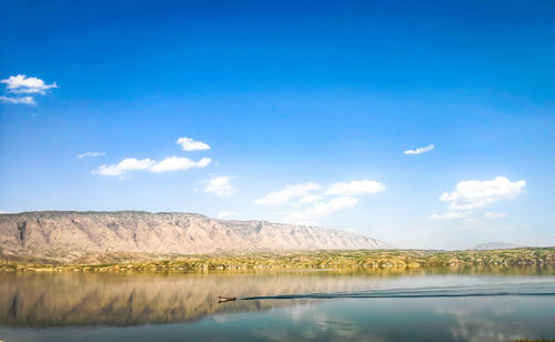 Scenic view of lake by mountain against sky