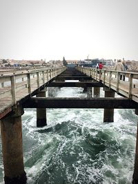 Bridge over river in city against clear sky