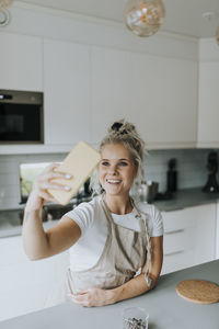 Smiling woman taking selfie in kitchen