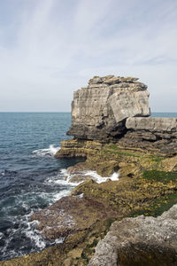 Rock formation on beach against sky