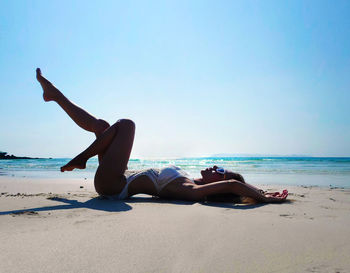 Man relaxing on beach against sky