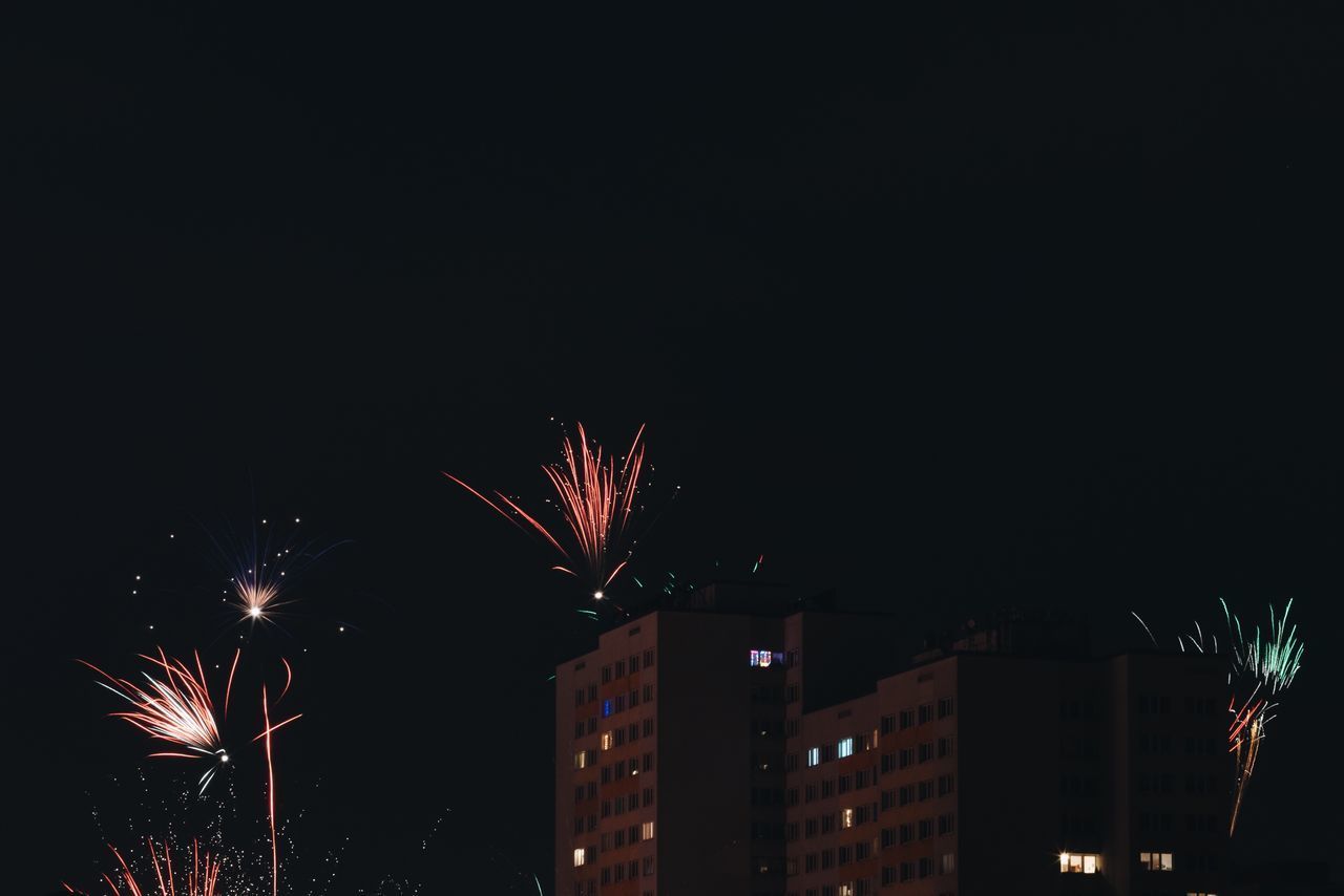 LOW ANGLE VIEW OF FIREWORK DISPLAY OVER CITY AT NIGHT