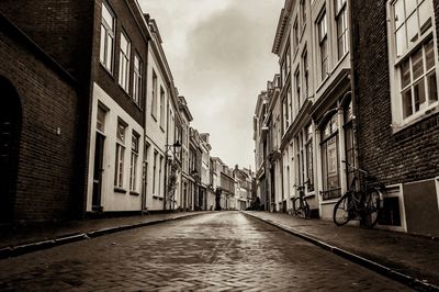 Empty road amidst buildings against sky