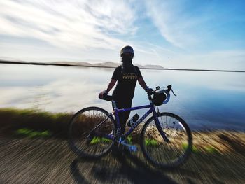 Man riding bicycle on water against sky