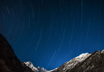 Star trail night photography with snow covered mountain peak