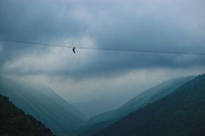 Low angle view of man ziplining against sky