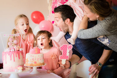 Mother at daughters blowing birthday candle at home