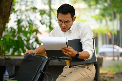 Young man using mobile phone while sitting in park