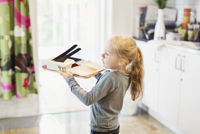 Side view of girl carrying food tray in preschool