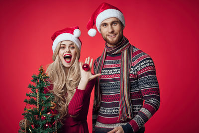 Portrait of smiling young man against red christmas tree