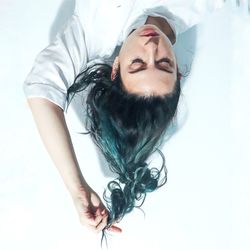 Portrait of young woman lying down against white background