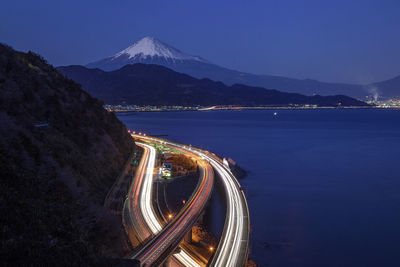 Light trails on road against sky in city at night