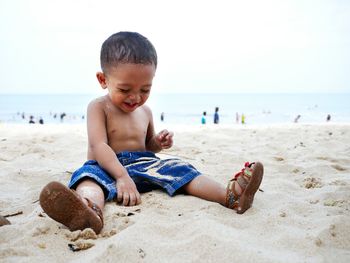 Close-up of boy playing on beach against sky