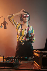 Portrait of young woman standing against illuminated string lights