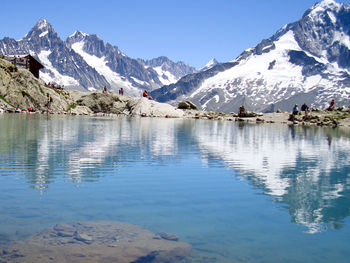 Scenic view of lake and snowcapped mountains against blue sky