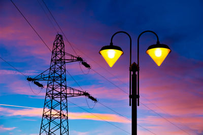 Low angle view of electricity pylon against sky during sunset