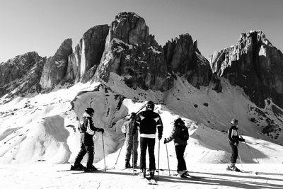 People skiing on snow field by rock formation