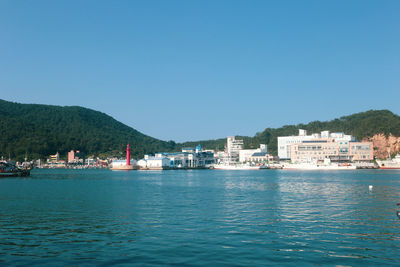 Sea by buildings against clear blue sky