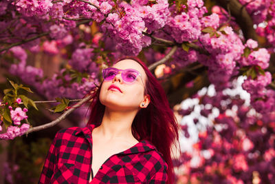 Portrait of woman with pink flowers against trees