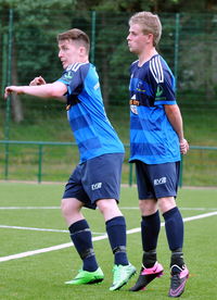 Full length of friends playing soccer on field