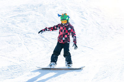 Full length of boy snowboarding in snow