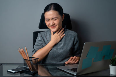 Young woman using mobile phone while sitting on table