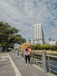 Woman standing by building against sky