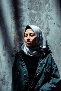 Portrait of young woman against wall