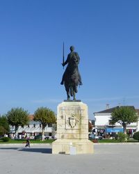Statue in city against clear blue sky