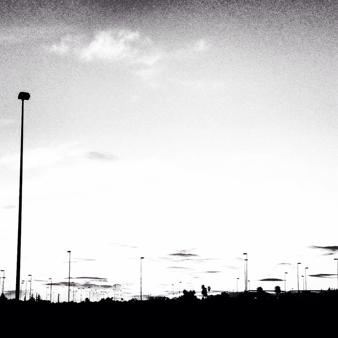 silhouette, street light, sky, low angle view, sunset, lighting equipment, copy space, dusk, tranquility, nature, electricity pylon, beauty in nature, outdoors, tranquil scene, cloud, cloud - sky, electricity, pole, scenics, no people