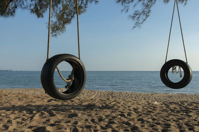 Bicycle wheel on beach against clear sky