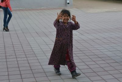 Full length portrait of happy homeless girl walking on street