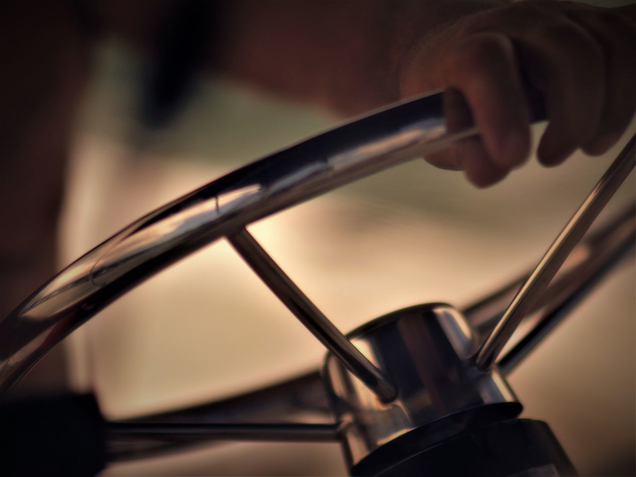 CLOSE-UP OF HUMAN HAND HOLDING METAL AGAINST BLURRED BACKGROUND