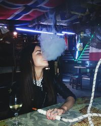 Woman smoking hookah while sitting in restaurant