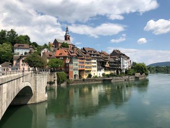 Buildings by river against sky in city