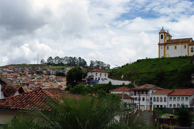 Buildings in town against cloudy sky