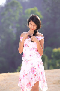 Portrait of beautiful young woman standing against pink background