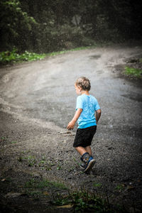 Rear view of boy running on road