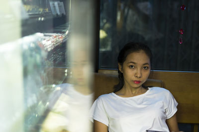 Portrait of woman standing by glass window