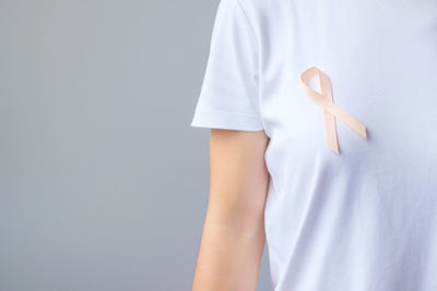 Midsection of woman standing against gray background