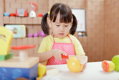 Cute girl looking away while sitting on table at home