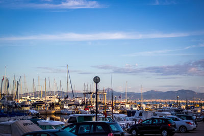 Boats in harbor against cloudy sky