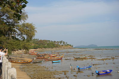 Boats moored on beach against sky