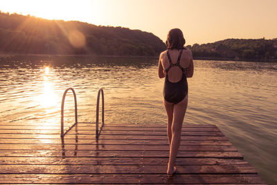 Young girl on a wooden pontoon by a lake in the evening at sunset