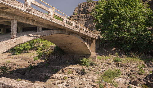 Arch bridge over rocks against trees