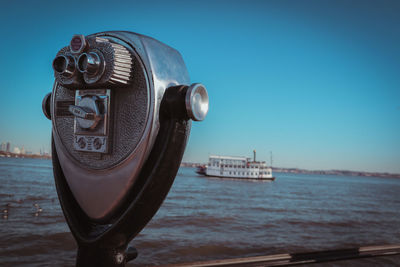 Close-up of coin-operated binoculars by sea against sky