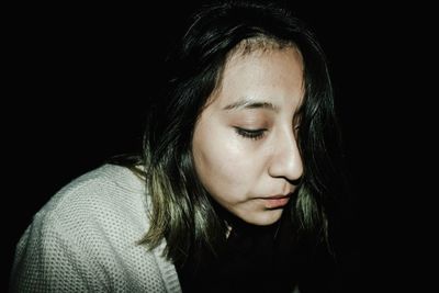 Close-up portrait of a beautiful young woman over black background